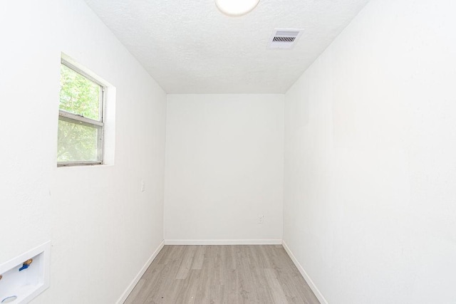 spare room with a textured ceiling and light wood-type flooring