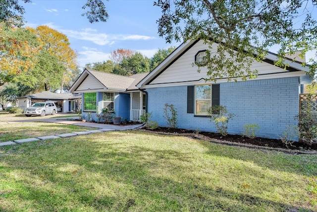 ranch-style home featuring a front lawn and covered porch