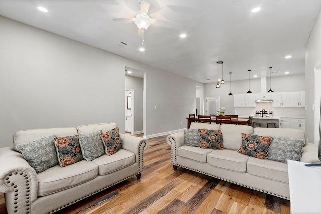 living area featuring ceiling fan, light wood-style flooring, recessed lighting, visible vents, and baseboards