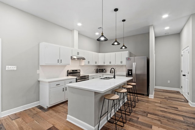 kitchen with stainless steel appliances, white cabinetry, sink, and an island with sink