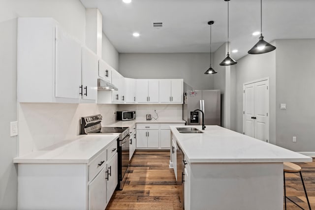 kitchen featuring stainless steel appliances, an island with sink, hanging light fixtures, and white cabinetry