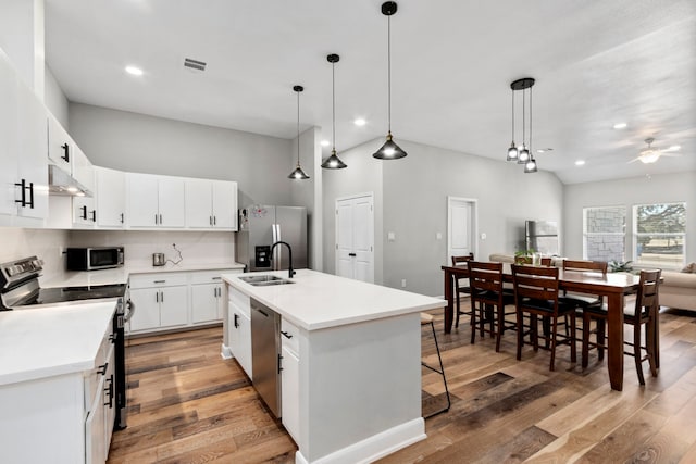 kitchen with light countertops, appliances with stainless steel finishes, an island with sink, and white cabinetry