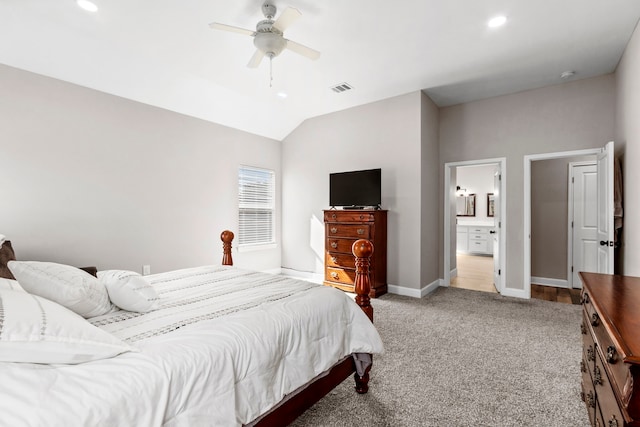 bedroom with light colored carpet, ceiling fan, vaulted ceiling, and ensuite bath