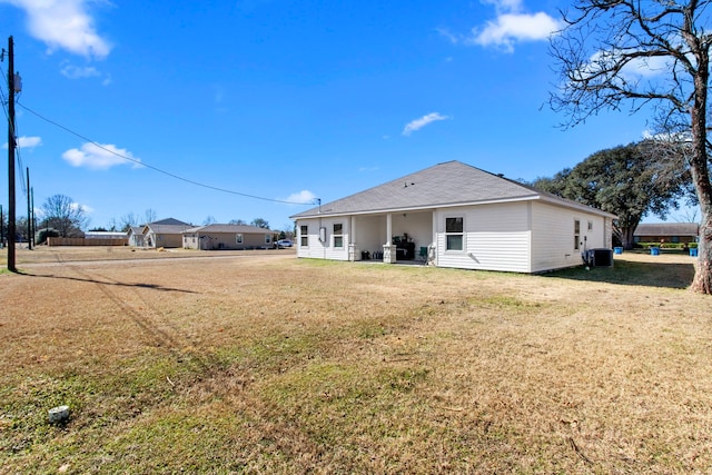 rear view of house featuring central AC and a lawn