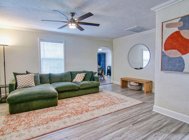 living room featuring hardwood / wood-style floors, crown molding, a textured ceiling, and ceiling fan