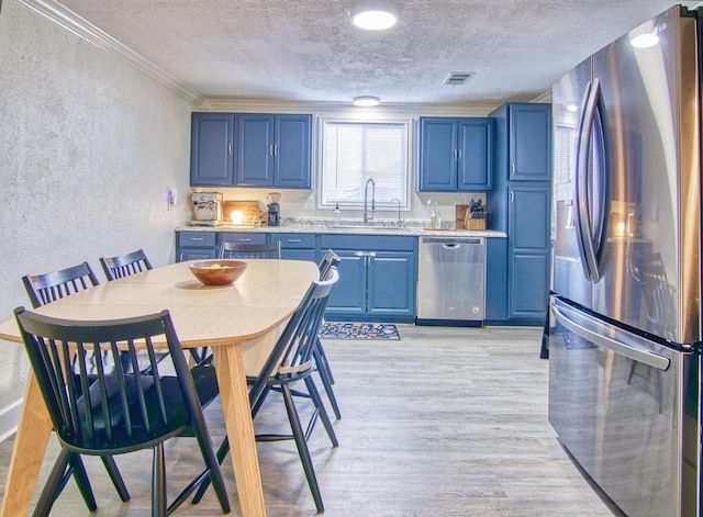 kitchen with sink, appliances with stainless steel finishes, a textured ceiling, blue cabinets, and light wood-type flooring