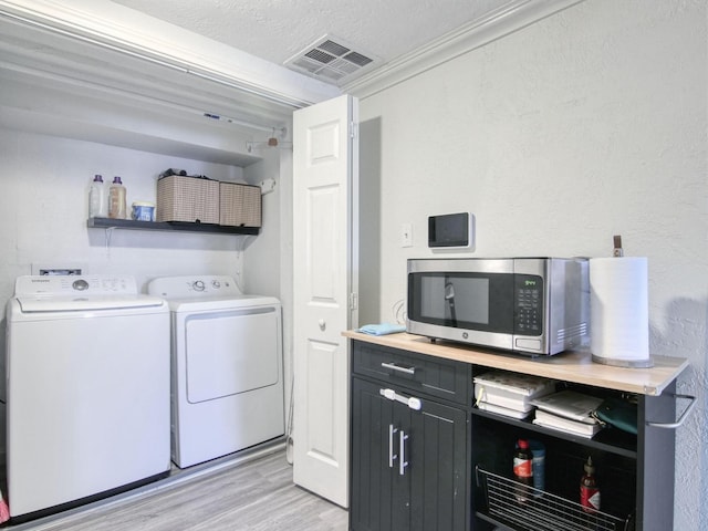 washroom featuring separate washer and dryer, a textured ceiling, and light hardwood / wood-style floors