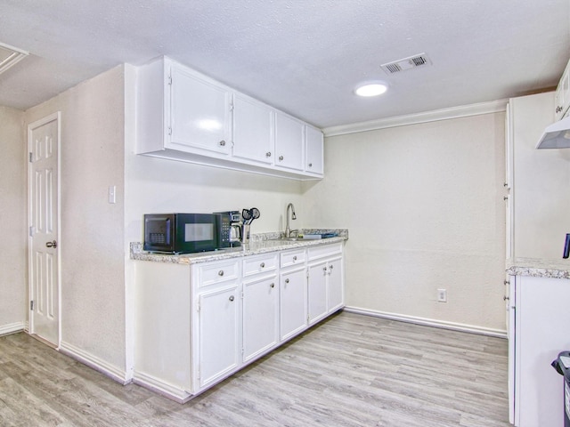 kitchen featuring white cabinetry, sink, light hardwood / wood-style floors, and a textured ceiling