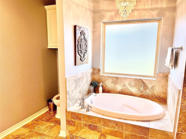 bathroom featuring a relaxing tiled tub, a notable chandelier, and toilet