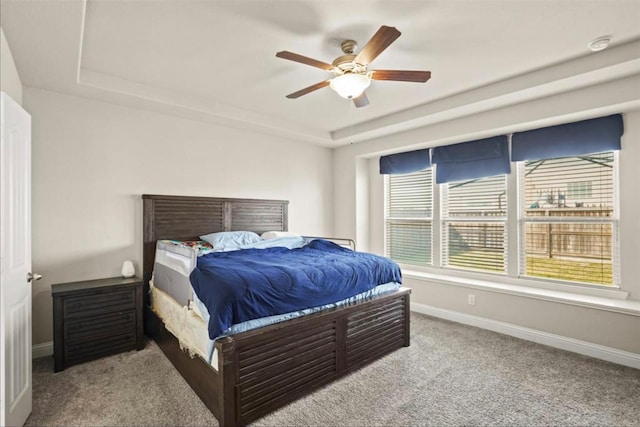 carpeted bedroom with a tray ceiling and ceiling fan