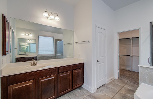bathroom featuring a tub, a walk in closet, tile patterned flooring, and vanity