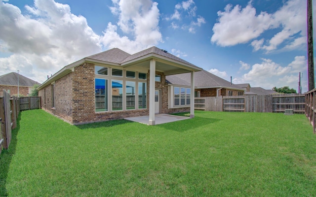 back of property with a fenced backyard, a yard, a patio area, and brick siding