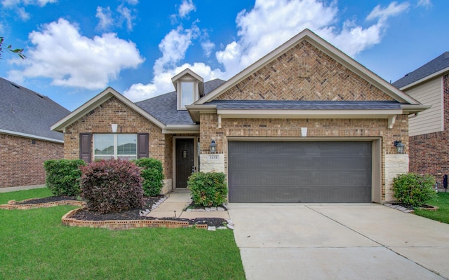 traditional-style home with brick siding, an attached garage, a front yard, and concrete driveway