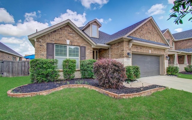 view of front facade with a front lawn, fence, brick siding, an attached garage, and driveway