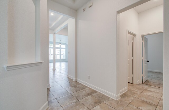 hall featuring baseboards and light tile patterned flooring