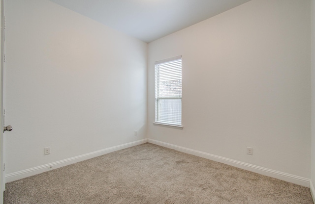 empty room with baseboards and light carpet