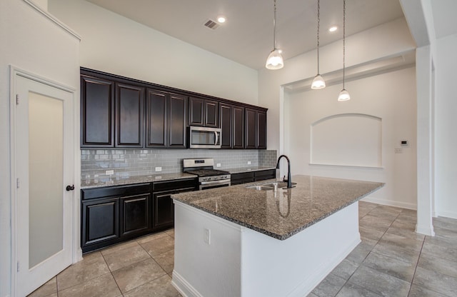 kitchen featuring a sink, dark stone countertops, stainless steel appliances, decorative backsplash, and visible vents