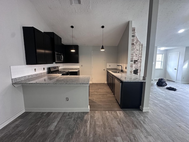 kitchen with appliances with stainless steel finishes, sink, kitchen peninsula, light stone countertops, and a textured ceiling