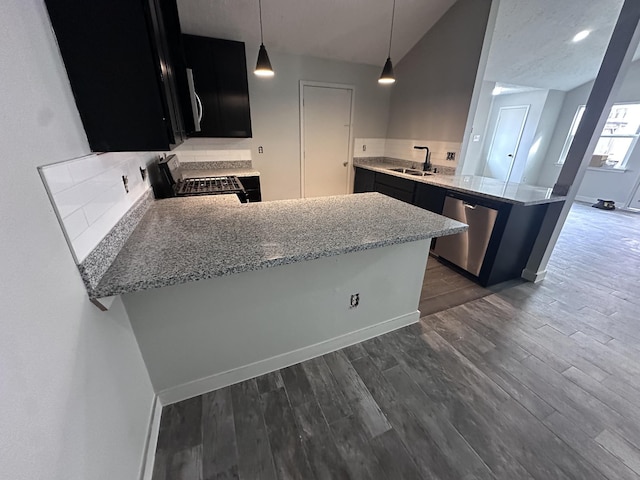 kitchen featuring sink, decorative light fixtures, appliances with stainless steel finishes, dark hardwood / wood-style floors, and kitchen peninsula