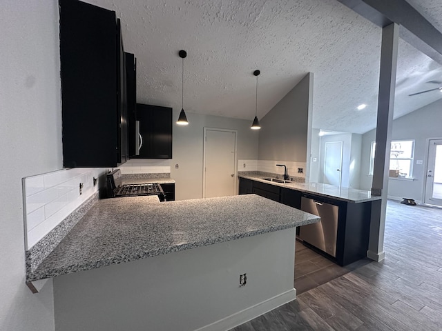 kitchen with decorative light fixtures, vaulted ceiling, a textured ceiling, kitchen peninsula, and stainless steel appliances