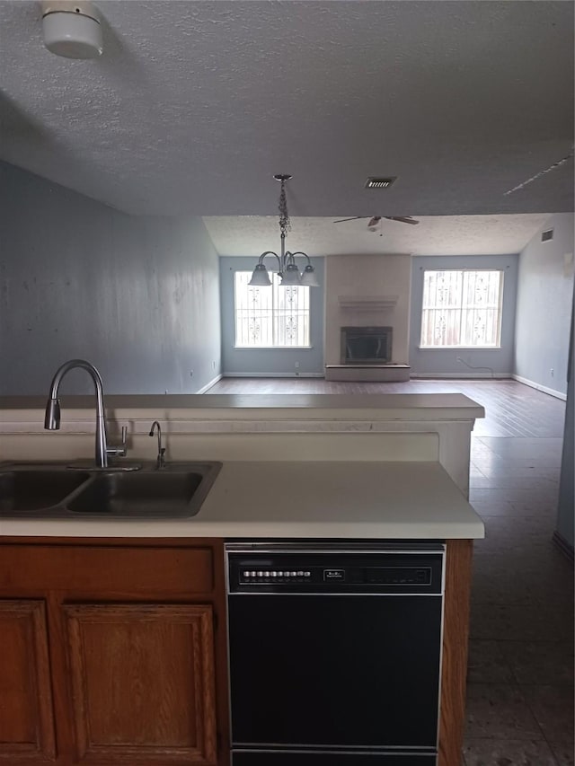 kitchen featuring pendant lighting, black dishwasher, sink, and a textured ceiling