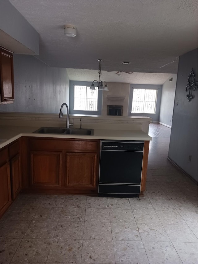 kitchen featuring hanging light fixtures, dishwasher, sink, and a textured ceiling