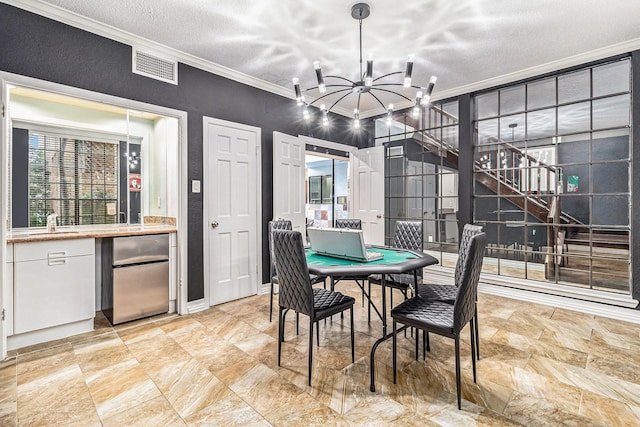 dining room featuring a notable chandelier, ornamental molding, and a textured ceiling