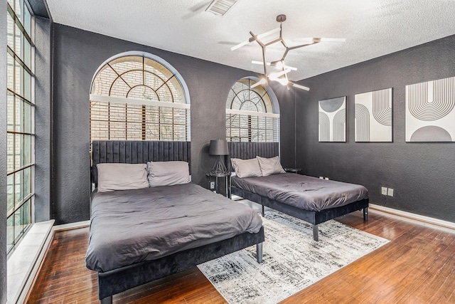 bedroom with hardwood / wood-style flooring, ceiling fan, and a textured ceiling