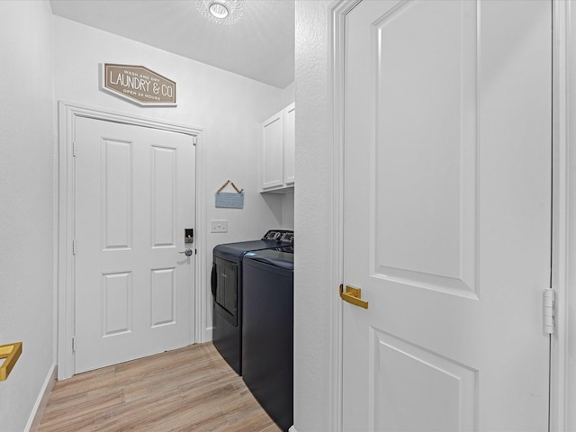 washroom featuring cabinets, separate washer and dryer, and light hardwood / wood-style flooring