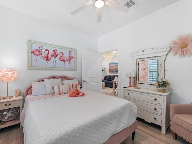 bedroom featuring ceiling fan with notable chandelier and light wood-type flooring