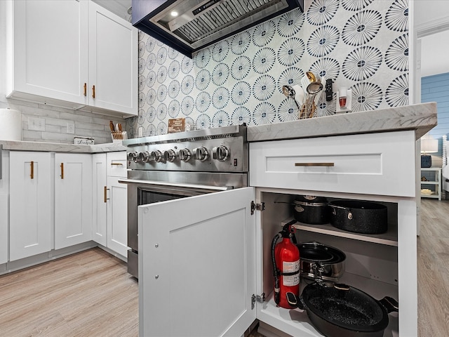 kitchen featuring premium range hood, tasteful backsplash, white cabinetry, high end range, and light hardwood / wood-style flooring