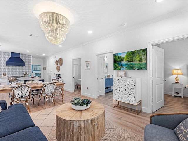 living room featuring crown molding, light hardwood / wood-style flooring, and a chandelier