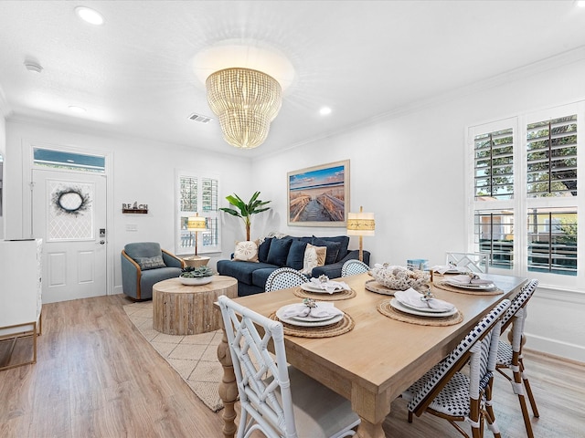 dining room featuring ornamental molding, light hardwood / wood-style flooring, and a notable chandelier