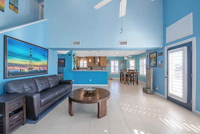 tiled living room with ceiling fan and a high ceiling