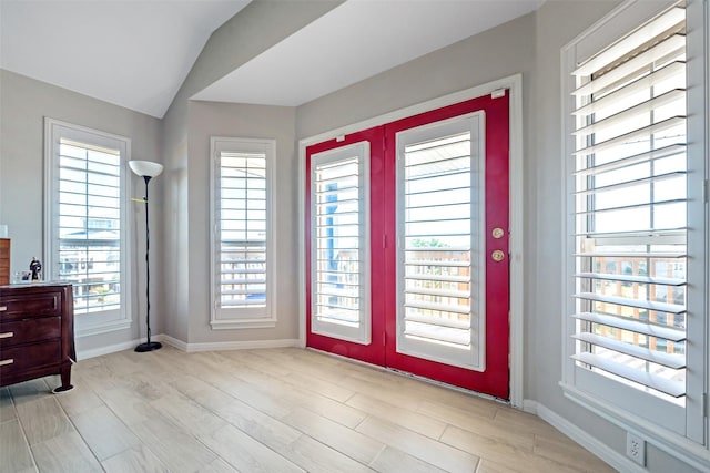 foyer featuring lofted ceiling, a healthy amount of sunlight, light hardwood / wood-style floors, and french doors