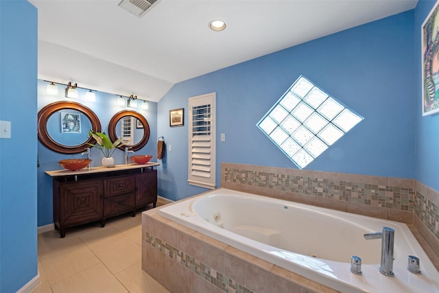 bathroom with a relaxing tiled tub, lofted ceiling, tile patterned flooring, and vanity