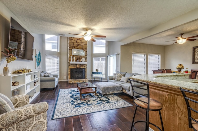 living room featuring a fireplace, plenty of natural light, dark hardwood / wood-style flooring, and a textured ceiling