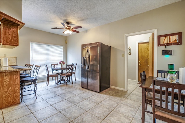 tiled dining room with ceiling fan and a textured ceiling