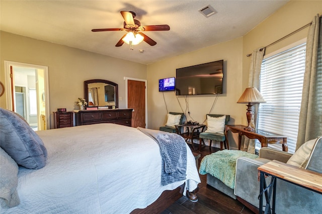 bedroom featuring connected bathroom, a textured ceiling, dark wood-type flooring, and ceiling fan