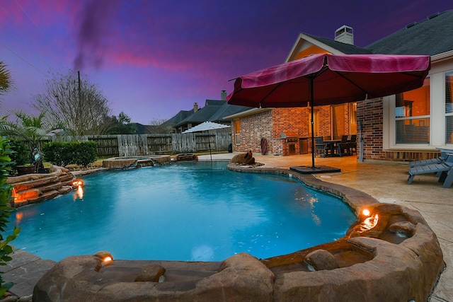 pool at dusk featuring an in ground hot tub and a patio area