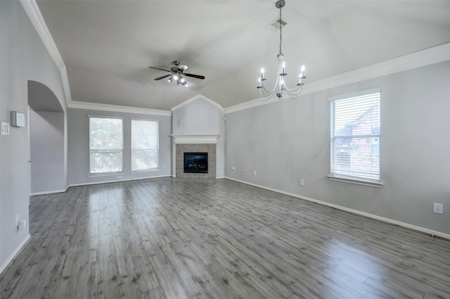 unfurnished living room with a tile fireplace, vaulted ceiling, hardwood / wood-style floors, and crown molding