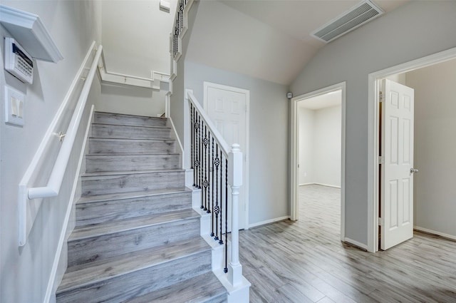 stairs with wood-type flooring and vaulted ceiling