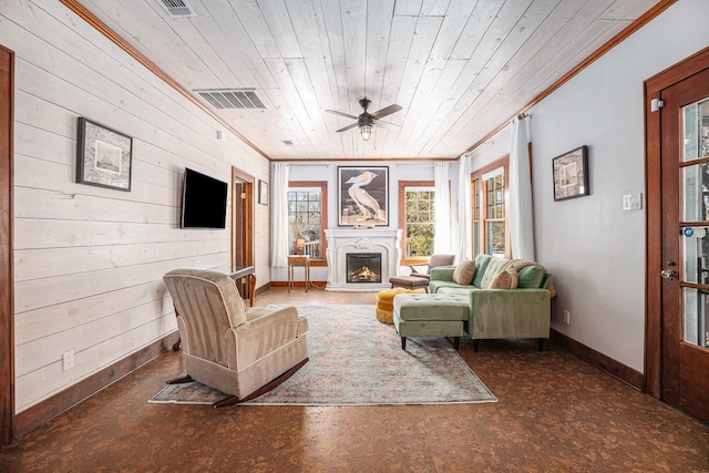 living room featuring crown molding, wood ceiling, ceiling fan, and wood walls