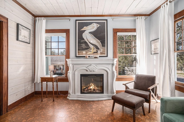 living area with wood ceiling, crown molding, and wood walls