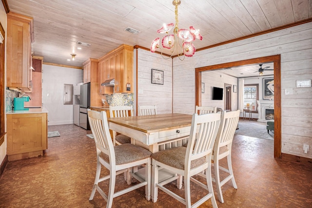 dining area featuring sink, wood ceiling, ornamental molding, wooden walls, and ceiling fan with notable chandelier