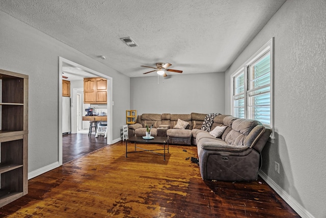 living room with ceiling fan, dark hardwood / wood-style floors, and a textured ceiling