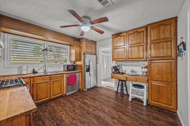 kitchen with wood counters, sink, dark wood-type flooring, and stainless steel appliances