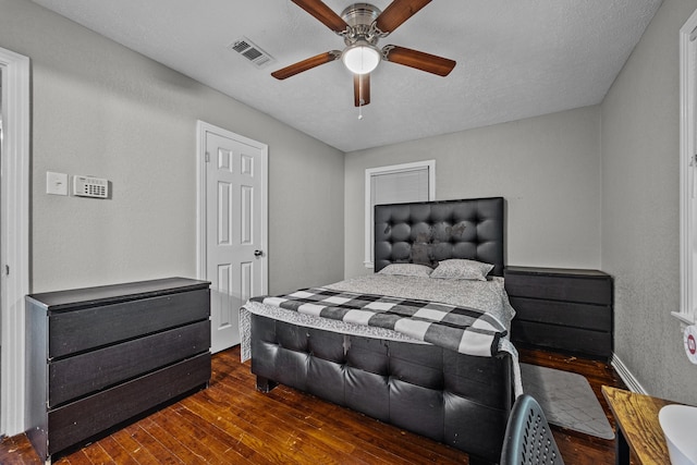 bedroom with dark hardwood / wood-style floors, a textured ceiling, and ceiling fan