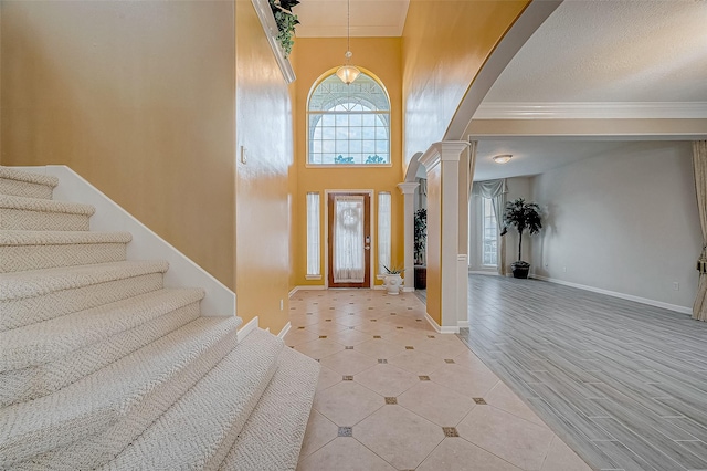 foyer entrance with decorative columns, a high ceiling, and light hardwood / wood-style floors