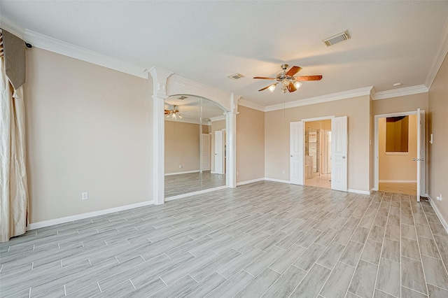 empty room featuring ceiling fan, ornamental molding, and decorative columns